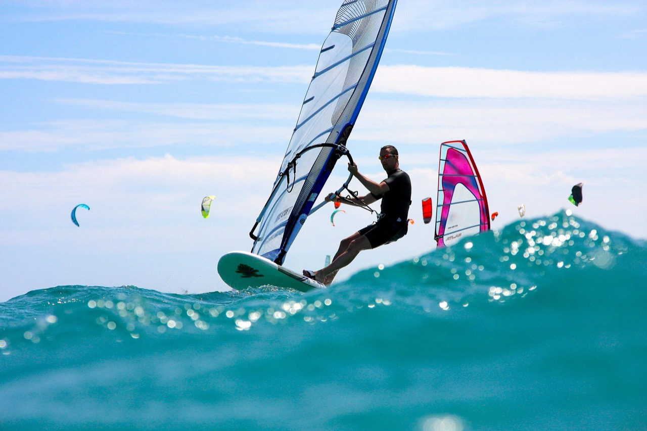 Windsurfing through waves at Koh Samui — kites visible in the background